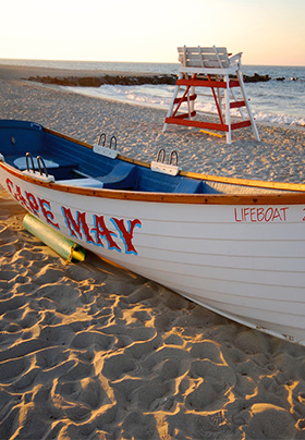Cape May Lifeguard white rowboat on red lettering of the name Cape May on the beach
